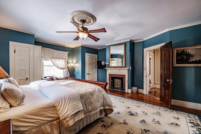 bedroom with ornamental molding, a fireplace, baseboards, and wood finished floors