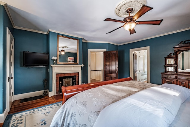 bedroom with a fireplace, ornamental molding, a ceiling fan, wood finished floors, and baseboards