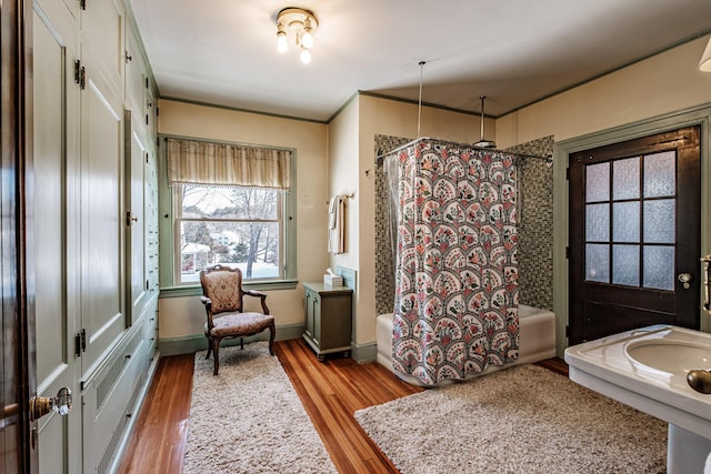 full bathroom with crown molding, baseboards, wood finished floors, and shower / bathtub combination with curtain