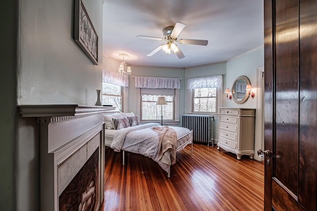 bedroom with ornamental molding, a ceiling fan, radiator heating unit, and wood finished floors