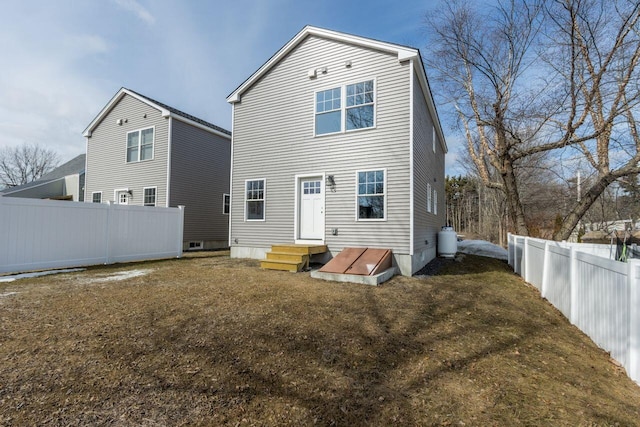 rear view of property featuring a yard, entry steps, and fence