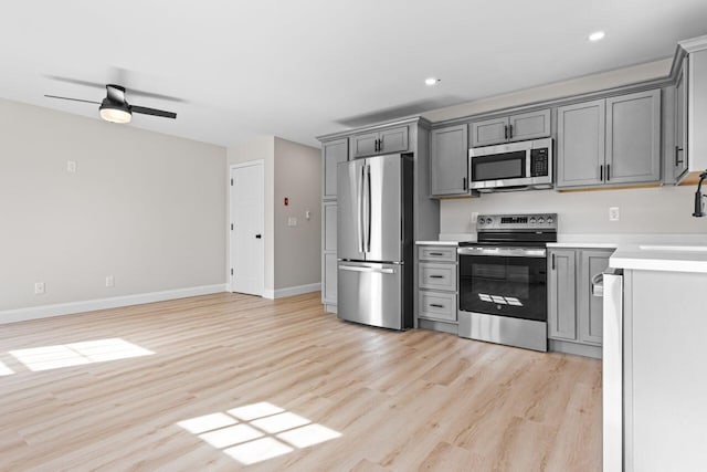 kitchen with stainless steel appliances, light wood-style floors, gray cabinets, and light countertops