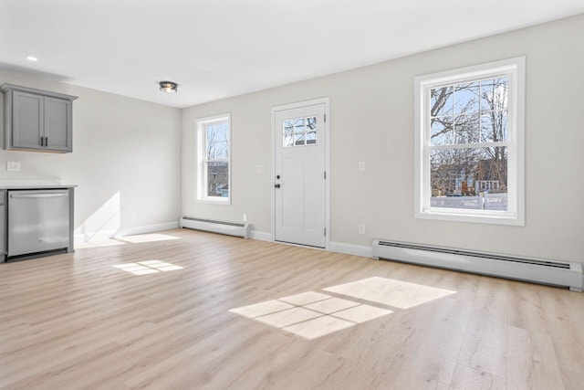 foyer entrance featuring a baseboard heating unit, light wood-style flooring, and a healthy amount of sunlight