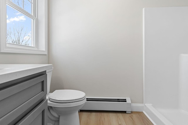 bathroom featuring toilet, a baseboard heating unit, wood finished floors, baseboards, and vanity