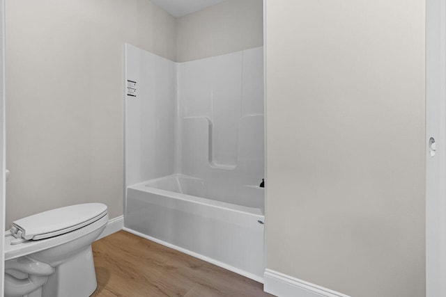 full bathroom with toilet, wood finished floors, baseboards, and shower / washtub combination