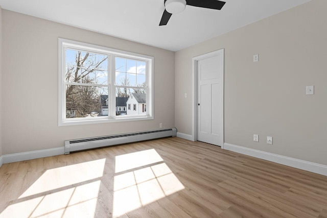 spare room featuring baseboard heating, baseboards, and wood finished floors