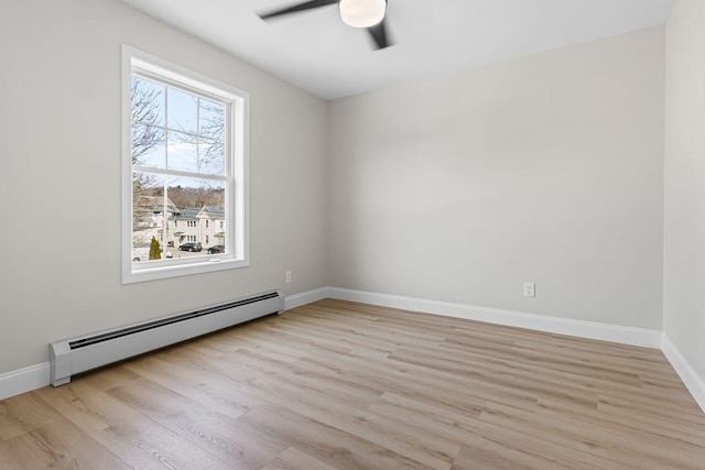 spare room featuring ceiling fan, baseboards, light wood-style floors, and a baseboard radiator