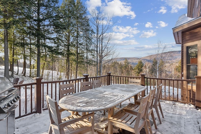 snow covered deck featuring outdoor dining space, a mountain view, and area for grilling