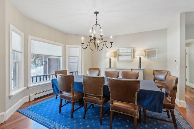 dining space featuring an inviting chandelier, a baseboard radiator, baseboards, and wood finished floors