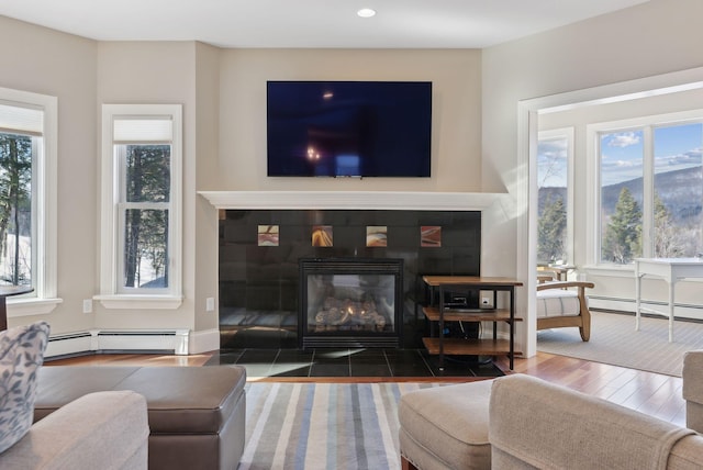 living room with a wealth of natural light, a fireplace, dark wood finished floors, and baseboard heating