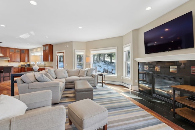 living room with recessed lighting, baseboard heating, dark wood-type flooring, and a tile fireplace