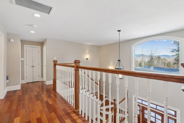 corridor with baseboards, visible vents, wood finished floors, an upstairs landing, and recessed lighting