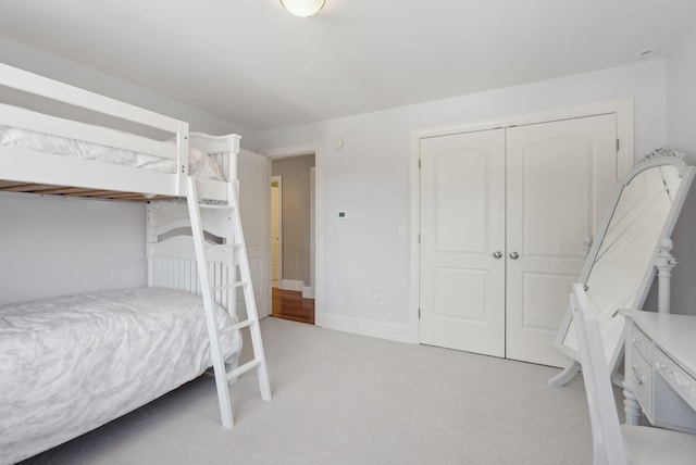 bedroom featuring light carpet, a closet, and baseboards