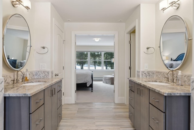 ensuite bathroom featuring a sink, two vanities, and connected bathroom