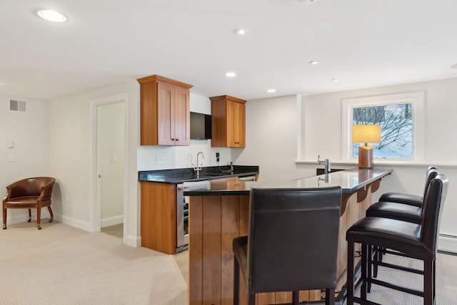 kitchen featuring dark countertops, recessed lighting, light colored carpet, visible vents, and a kitchen bar