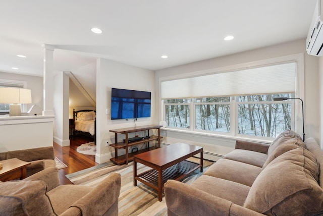 living area with recessed lighting, a baseboard heating unit, baseboards, an AC wall unit, and light wood-type flooring