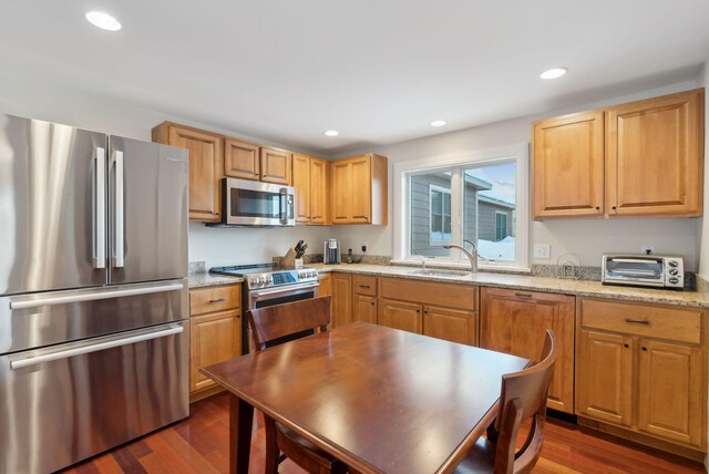 kitchen featuring a toaster, light stone counters, dark wood-type flooring, stainless steel appliances, and recessed lighting