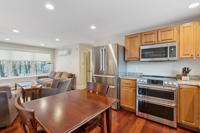 kitchen with light stone counters, dark wood-style floors, stainless steel appliances, recessed lighting, and a wall mounted air conditioner