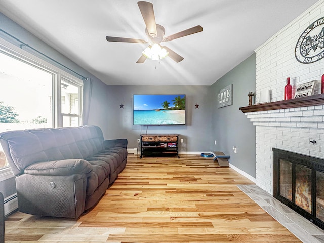 living area featuring a fireplace, light wood finished floors, a baseboard heating unit, a ceiling fan, and baseboards