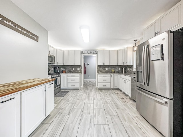 kitchen with stainless steel appliances, white cabinets, and tasteful backsplash