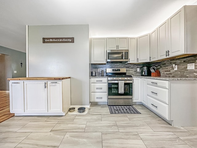 kitchen with stainless steel appliances, light stone countertops, white cabinets, and tasteful backsplash