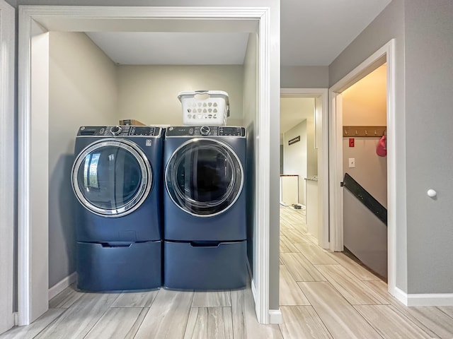 clothes washing area with laundry area, wood tiled floor, baseboards, and washer and dryer