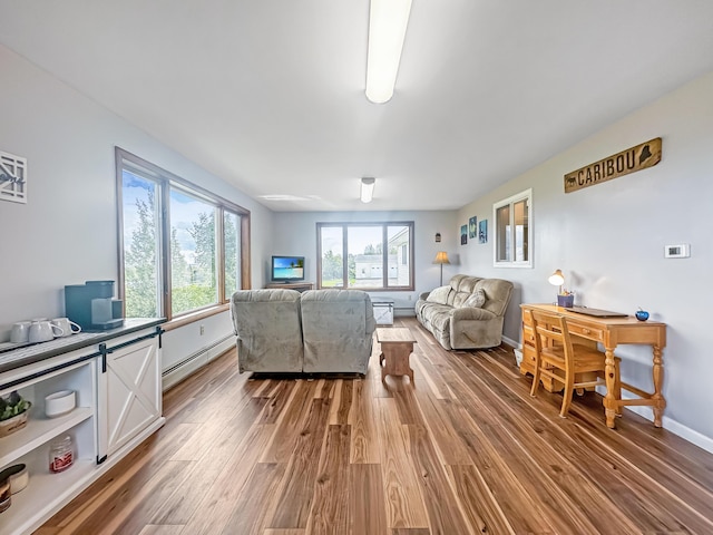 living area featuring baseboards, a healthy amount of sunlight, baseboard heating, and wood finished floors