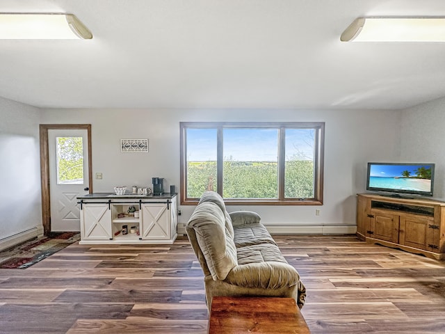 living area featuring a baseboard heating unit, baseboards, and wood finished floors