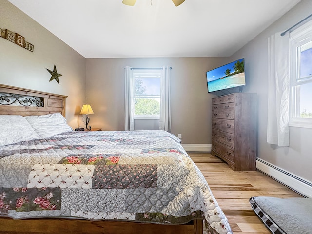 bedroom with light wood-style floors, baseboards, a baseboard heating unit, and ceiling fan