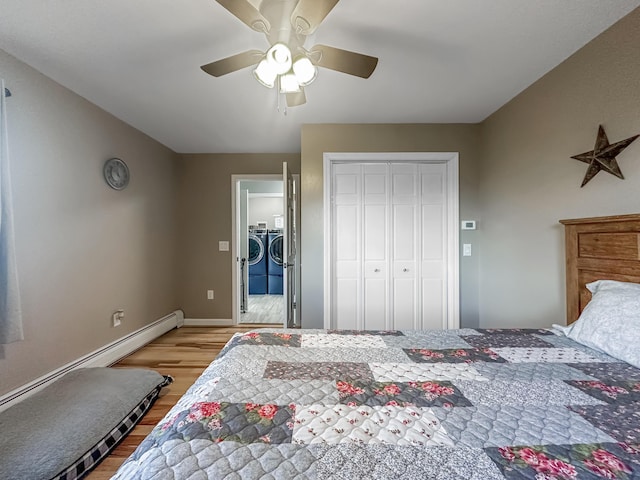 bedroom with a baseboard radiator, ceiling fan, wood finished floors, independent washer and dryer, and a closet