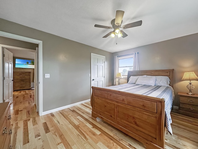 bedroom with light wood-style floors, ceiling fan, and baseboards