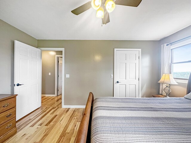 bedroom with light wood-style flooring, baseboards, and a ceiling fan