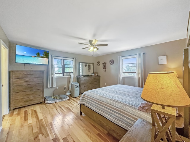 bedroom featuring light wood-type flooring, ceiling fan, and multiple windows