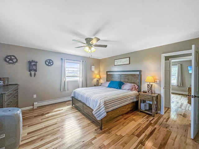 bedroom featuring light wood-style floors, multiple windows, and a baseboard heating unit