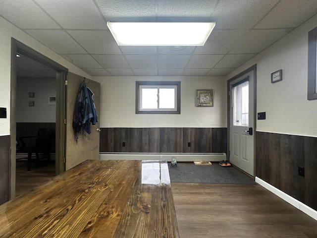 spare room featuring a wainscoted wall, dark wood finished floors, a paneled ceiling, and wooden walls