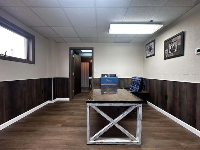 interior space featuring a paneled ceiling, a wainscoted wall, wooden walls, and dark wood-style floors