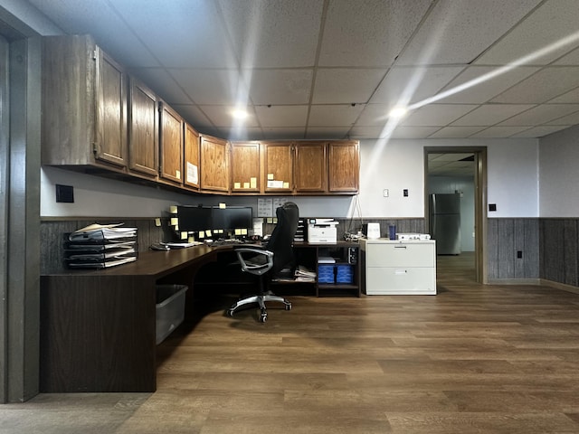 office with a paneled ceiling, dark wood-style floors, built in desk, and wainscoting