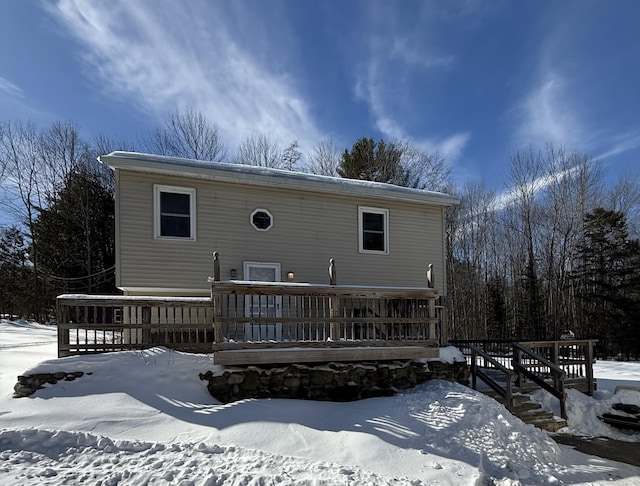 snow covered house with a wooden deck