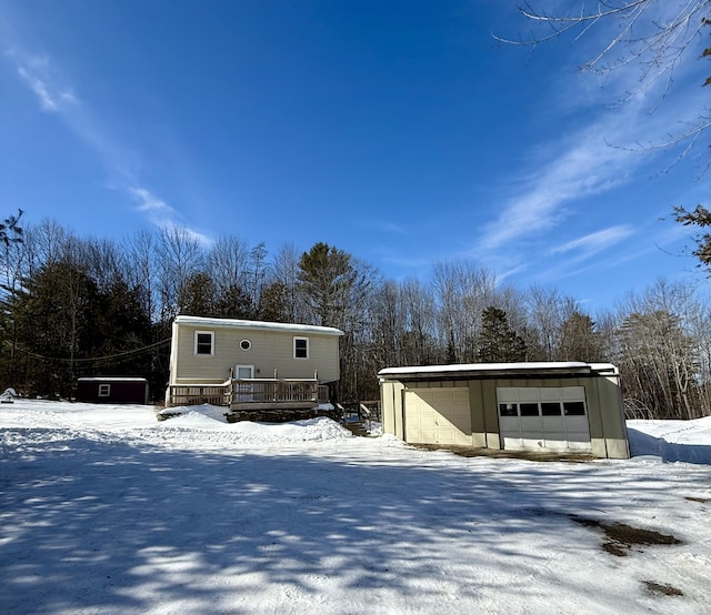 view of front of house with a wooden deck, a detached garage, and an outdoor structure