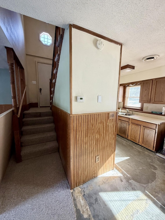 interior space with a wainscoted wall, a textured ceiling, and wood walls