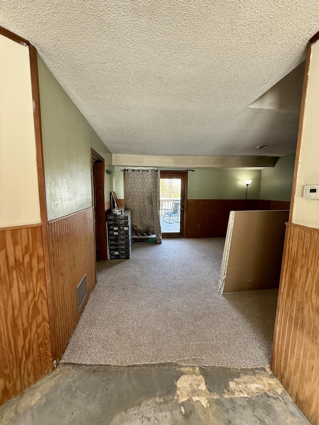 interior space with a wainscoted wall, wood walls, and a textured ceiling