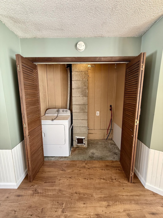 laundry area featuring laundry area, wainscoting, light wood-style flooring, and a textured ceiling