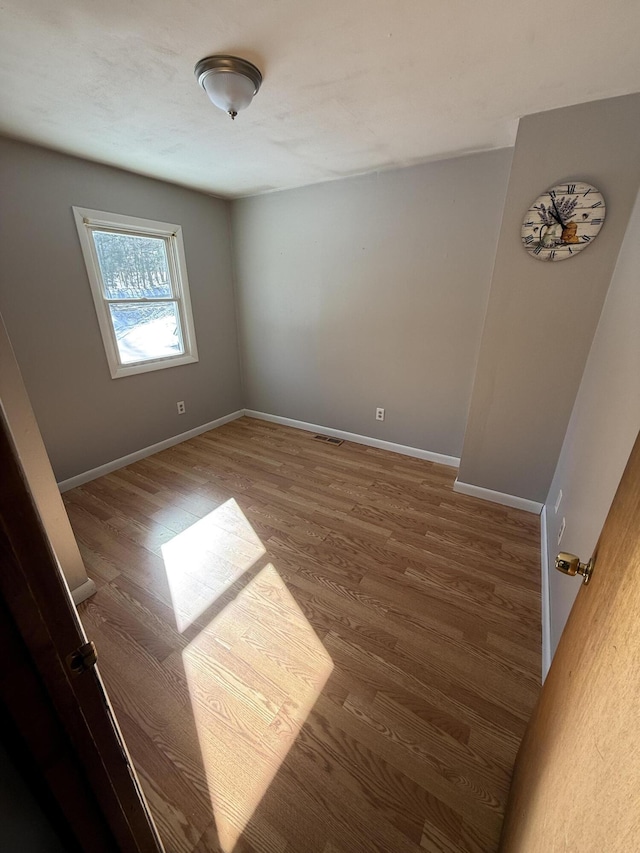 spare room with visible vents, baseboards, and wood finished floors