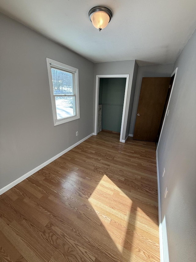 unfurnished bedroom featuring light wood-style floors, a closet, and baseboards