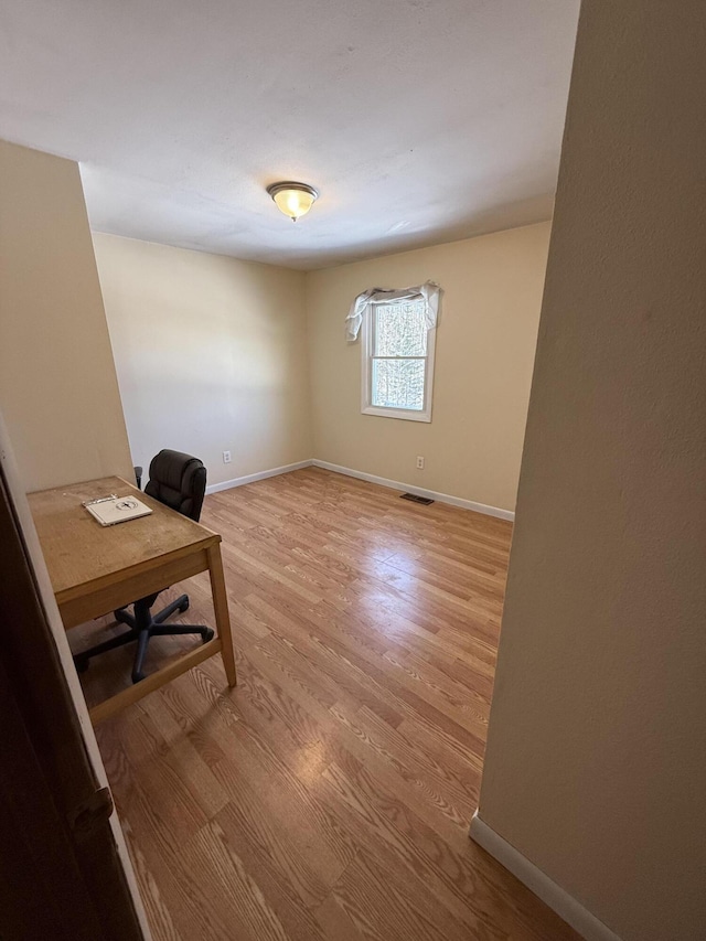 unfurnished office featuring light wood-style floors, visible vents, and baseboards