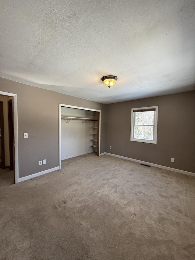 unfurnished bedroom featuring a textured ceiling, a closet, visible vents, and baseboards