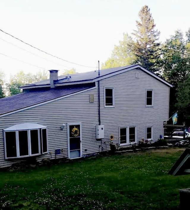 back of property featuring a lawn and a chimney