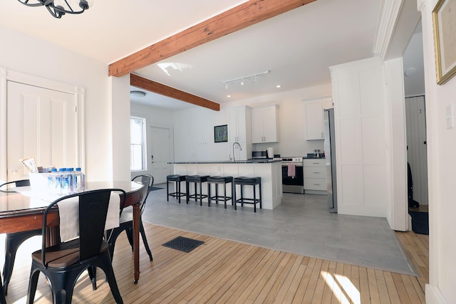 dining area featuring light wood-style floors and beam ceiling