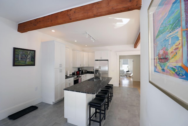 kitchen with appliances with stainless steel finishes, white cabinets, a kitchen island, beamed ceiling, and a kitchen bar