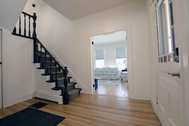 foyer with stairs, light wood-type flooring, a baseboard radiator, and baseboards